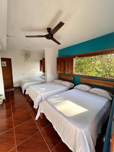 Casa Italia Guest House في تاجانجا: صف من الأسرة في غرفة مع مروحة سقف