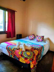 Depto 2 Chelson centro في فيلا جيزيل: غرفة نوم مع سرير ملون مع المناشف عليها