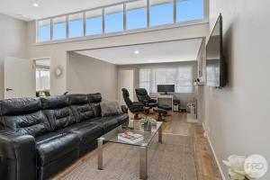 a living room with a black leather couch and chairs at LUXURY PET-FRIENDLY's BENDIGO ACCOMMODATION 4 BEDROOM 2 BATHROOMS ENTIRE HOME WALK TO BENDIGO CBD LAKE EASTER FESTIVAL Bendigo Regional Tennis Centre BRTC Central Deborah Gold Mine Bendigo Art Gallery Golden Dragon Museum Rosalind Park The Great Stupa in Bendigo