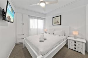 a white bedroom with a white bed and a television at Poolside Bliss in Maroochydore +10 photos