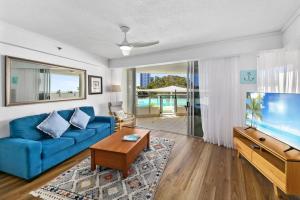 a living room with a blue couch and a fish tank at Poolside Bliss in Maroochydore