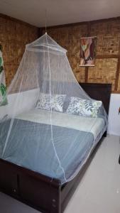 a bed with a net on it in a room at Nipaville Haven in Moalboal