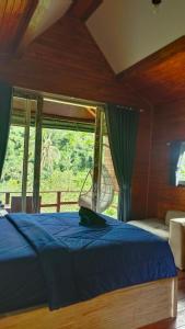 a bedroom with a blue bed and a window at Bali namping in Petang