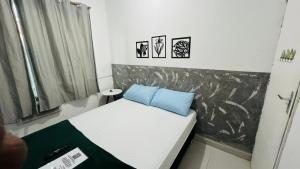 Quero mais arraial suites في أرايال دو كابو: غرفة صغيرة مع سرير ووسادتين زرقاوين