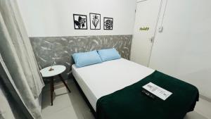 Quero mais arraial suites في أرايال دو كابو: غرفة نوم صغيرة مع سرير وطاولة