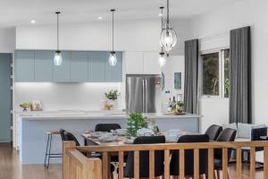 15 Scrub Rd - A Modern Coastal Luxury Retreat في كولوم بيتش: مطبخ وغرفة طعام مع طاولة وكراسي
