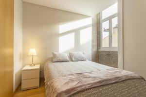 a bedroom with a large bed with a window at Bright Luxury Apartment in Viana do Castelo