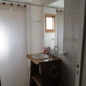 Un baño pequeño con lavabo y espejo. en Cabañas Agua de Piedra, en Villa Giardino