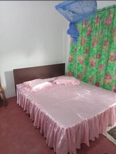 a bed with a pink bed skirt on it at Uva Guest Udawewa in Diyatalawa