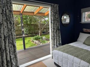 a bedroom with a bed and a sliding glass door at Unique Beachside Home in Eastbourne in Lower Hutt