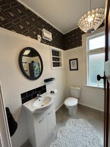 a bathroom with a sink and a toilet and a mirror at Unique Beachside Home in Eastbourne in Lower Hutt