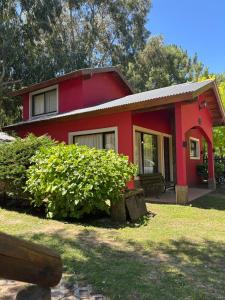 een rood huis met een veranda en een tuin bij Cabaña La Yuli in Santa Teresita