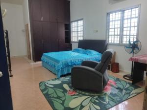 Un dormitorio con una cama y una silla dentro. en The Scholar's Den Homestay, en Kampong Bukit Kechil