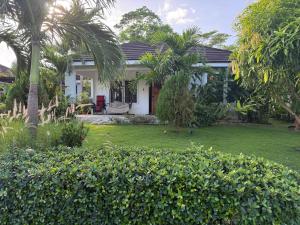 a white house with palm trees and a yard at Sweet Oasis in Mammee Bay