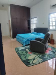 Un dormitorio con una cama y una silla sobre una alfombra. en The Scholar's Den Homestay, en Kampong Bukit Kechil