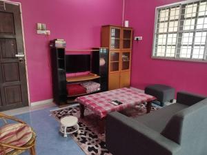 Una sala de estar con paredes rosas y un sofá y una mesa. en The Scholar's Den Homestay, en Kampong Bukit Kechil 17 fotos más