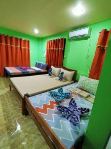 two beds in a room with green walls at Charming Urban Hideout in Puerto Princesa City