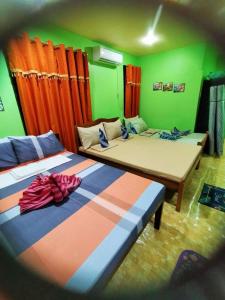 two beds in a room with green and orange at Charming Urban Hideout in Puerto Princesa City