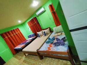 two beds in a room with green walls at Charming Urban Hideout in Puerto Princesa City