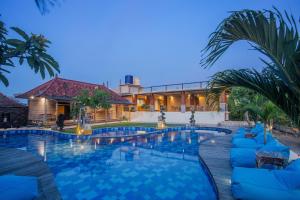 a swimming pool with blue chairs and a building at D'Gume Villas Lembongan in Nusa Lembongan