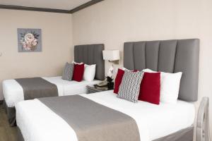 two beds in a hotel room with white and red pillows at Hotel Santander Plaza in Guatemala