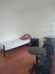 een kleine kamer met een bed en een tafel en stoelen bij Casa #4 Studios in San Pedro