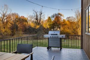 Una parrilla en un porche cubierto con una mesa y sillas. en Family Staycation Retreat 7BDR Sauna Games, 