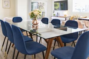 a dining room with a glass table and blue chairs at 5 Star Private House 5 rooms in Los Angeles