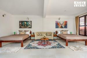 une chambre avec deux lits, un canapé et un tapis dans l'établissement StayVista at Hermitage 4BR - Boutique Stay - Relax in Nature, à Irpu 27 autres photos