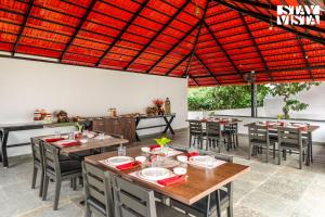 un restaurant avec des tables et des chaises et un toit rouge dans l'établissement StayVista at Hermitage 4BR - Boutique Stay - Relax in Nature, à Irpu