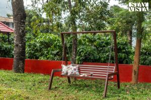 une balançoire avec un coussin assis dessus dans l'herbe dans l'établissement StayVista at Hermitage 4BR - Boutique Stay - Relax in Nature, à Irpu