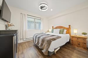 a white bedroom with a bed and a tv at Whistler Lakeside Hideaway in Whistler +47 photos