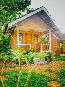 a small yellow house with a large front porch at The Village Eco-Bungalows in Salvacion, Busuanga in Busuanga