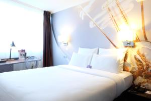 une chambre avec un grand lit blanc avec une fenêtre dans l'établissement Mercure Paris Malakoff Parc des Expositions, à Malakoff