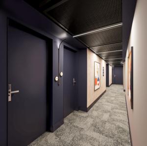 a corridor with dark blue doors and a hallway with paintings at Hampton By Hilton Manchester City Centre in Manchester