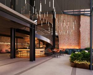 a lobby with a staircase and tables and chairs at Hampton By Hilton Manchester City Centre in Manchester +1 photo