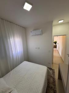 Praia Grande Boqueirão في برايا جراندي: غرفة نوم بسرير ابيض وممر