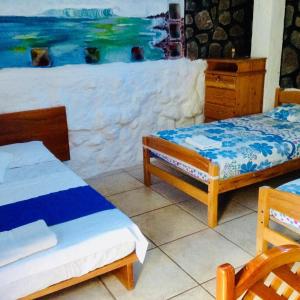 Una habitación con dos camas y un cuadro en la pared. en Penguin Hostel, en Puerto Ayora