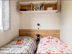 a bedroom with a bed and a book shelf at Mobil-home à Pordic 4 pers. avec Terrasse - API-1-52-1204 in Pordic