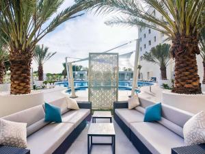 a resort patio with couches and palm trees and a pool at Mercure Sohar in Sohar