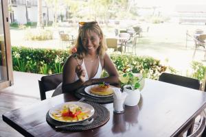 een vrouw die aan een tafel zit met een bord eten bij Ocean 101 Beach Resort in General Luna