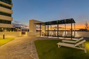 a building with a patio with tables and benches at The Corso - Central Maroochydore Apartment in Maroochydore
