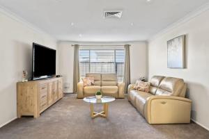 een woonkamer met een bank en een flatscreen-tv bij Sandy Serenity - Pet Friendly Beach House in The Entrance