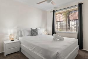 een witte slaapkamer met een groot wit bed en een raam bij Sandy Serenity - Pet Friendly Beach House in The Entrance