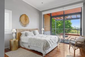 Hilltop Hideaway Family Escape في Merewether: غرفة نوم بيضاء مع سرير وشرفة