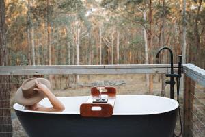 a woman is sitting in a bath tub with at Kookaburra Ridge in Wyee