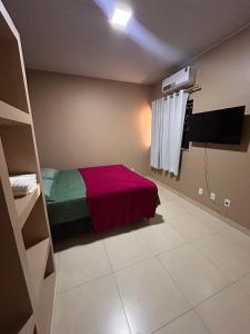 a bedroom with a bed with a red and green blanket at Residencial Roma in Palmas