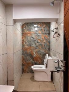 a bathroom with a toilet and a stone wall at Ambassador Stayz By JA Luxus in Jāmb