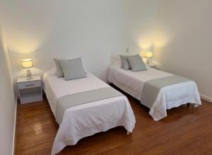 two beds in a white room with two lamps at The Marseille Oasis in La Porteña