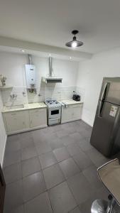 a large kitchen with white cabinets and a refrigerator at The Marseille Oasis in La Porteña